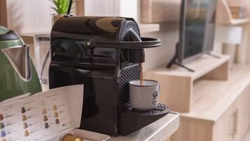 Una cafetera sirviendo café en una taza, una tetera verde y un menú con opciones de café.
