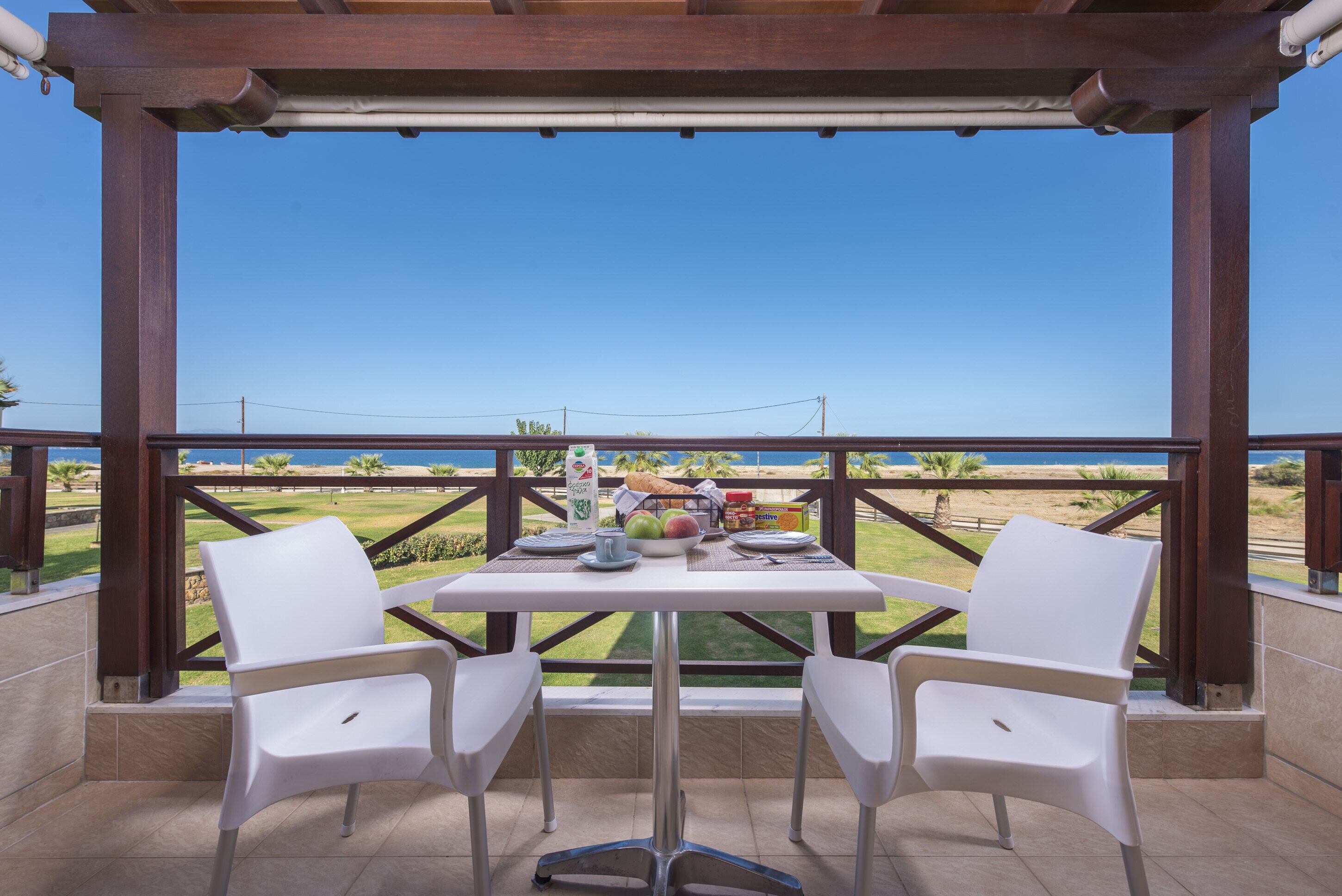 A balcony with a table set for two, overlooking a beach.