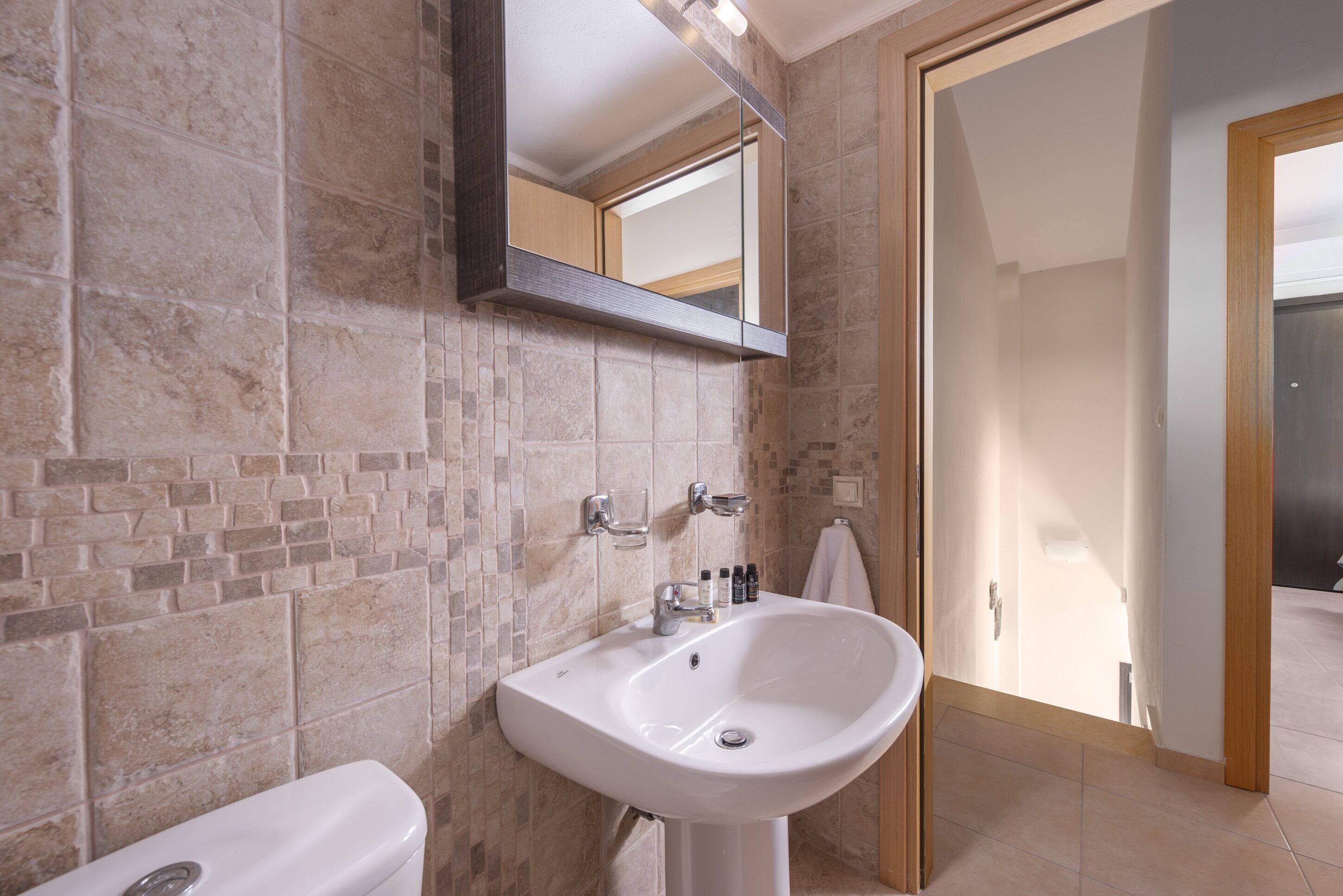 A bathroom with a white sink, a mirror, and a toilet.