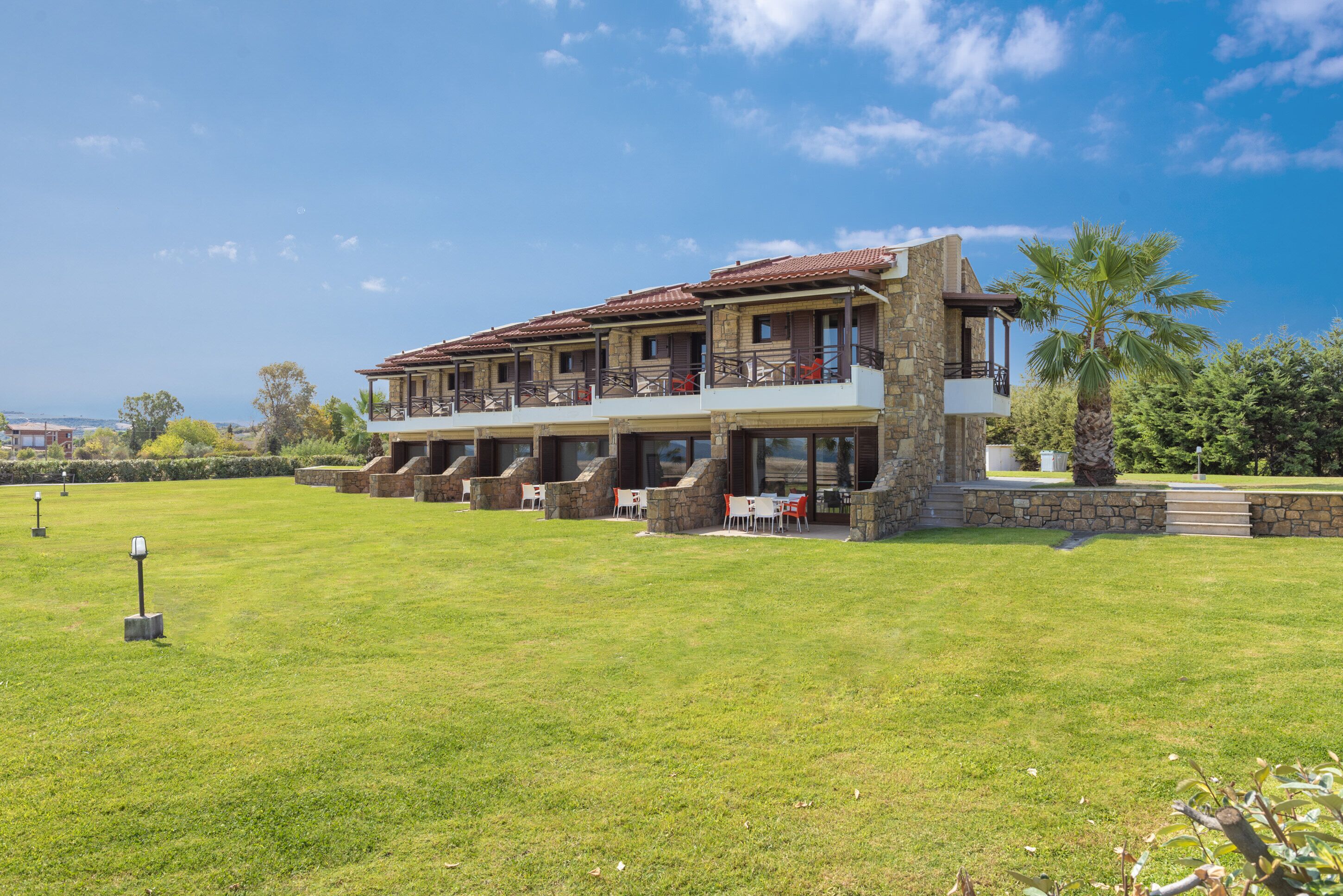 A two-story building with a stone facade, multiple balconies, and outdoor seating areas.