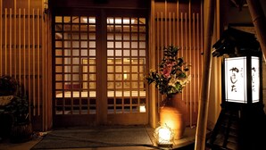 A traditional Japanese entrance with sliding doors, a flower arrangement, and a lantern. - Yamashita (Kanazawa)