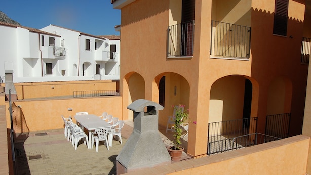 A courtyard with a stone fountain, white outdoor furniture, and a potted plant. - Casa Cristina - Convenient, functional and comfortable house (Orosei)