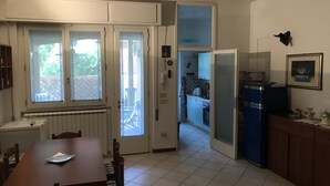 A compact kitchen with a dining area, a refrigerator, and a window overlooking a balcony. - Small villa in a great location (Viareggio)
