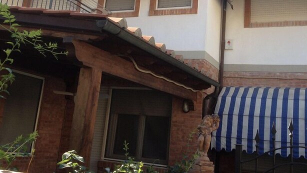 A two-story building with blue and white striped awnings over the windows and a staircase leading to the upper floor. - Small villa in a great location (Viareggio)