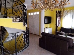 Une pièce dotée d’un escalier, d’un téléviseur à écran plat, d’un canapé et d’un lustre.