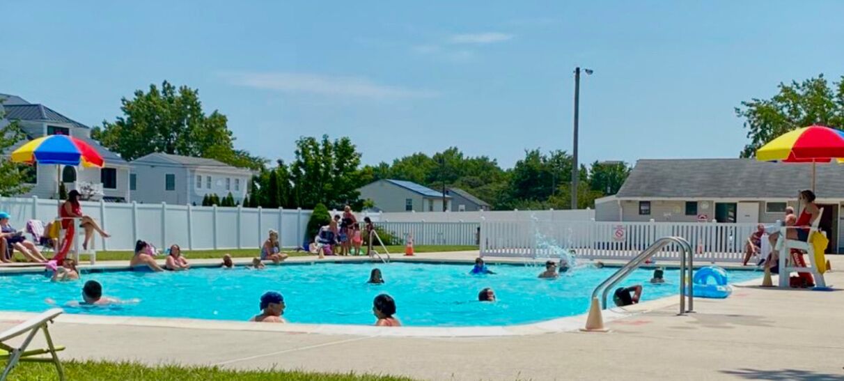 A swimming pool area with multiple lanes, a diving board, and a lifeguard stand.