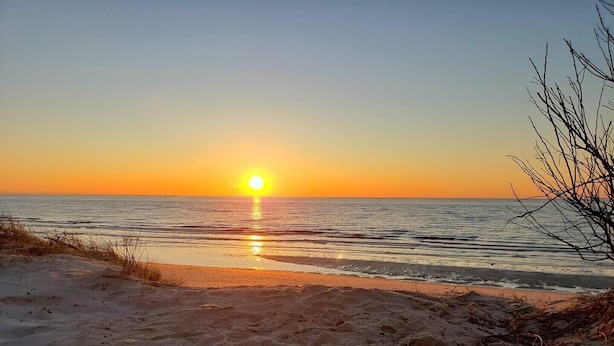 En strand med en solnedgång över havet.