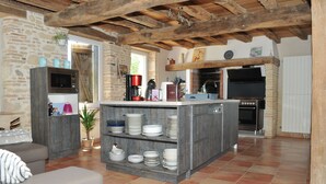 Une cuisine dotée d’un îlot central, de murs en pierre et d’un plafond en bois rustique.