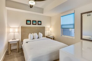 A hotel room with a bed, two bedside tables with lamps, a large mirror, and three framed pictures on the wall.