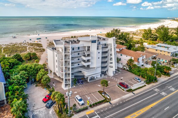 A multi-story hotel with a parking lot and a view of the beach.