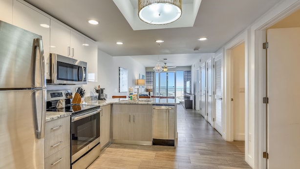 A modern kitchen with stainless steel appliances, wooden cabinets, and a central island. - ☀️Oceana 202 West☀️Beachfront☀️Private Balcony☀️Direct Beach Access (Treasure Island)