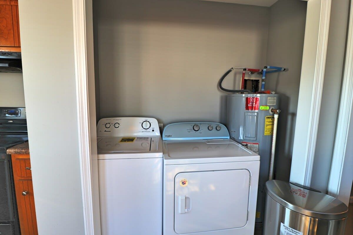 Un espace buanderie compact comprenant deux machines à laver et un chauffe-eau.