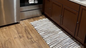 Een kleine keuken met roestvrijstalen apparatuur, houten kastjes en een marmeren aanrecht.