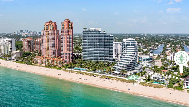 A coastal cityscape with high-rise buildings, a beach, and a marina.