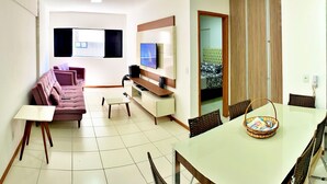 A living room with a sofa, TV, and a dining area with a table and chairs.