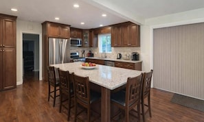 A kitchen with wooden cabinets, a granite countertop, and a stainless steel refrigerator.