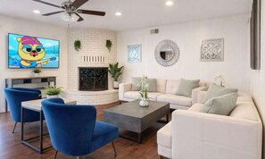 A living room with a fireplace, a television, a ceiling fan, and a sofa.