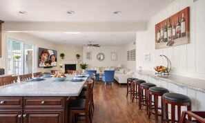 A spacious kitchen with a large island, bar stools, and a dining area with a blue chair.