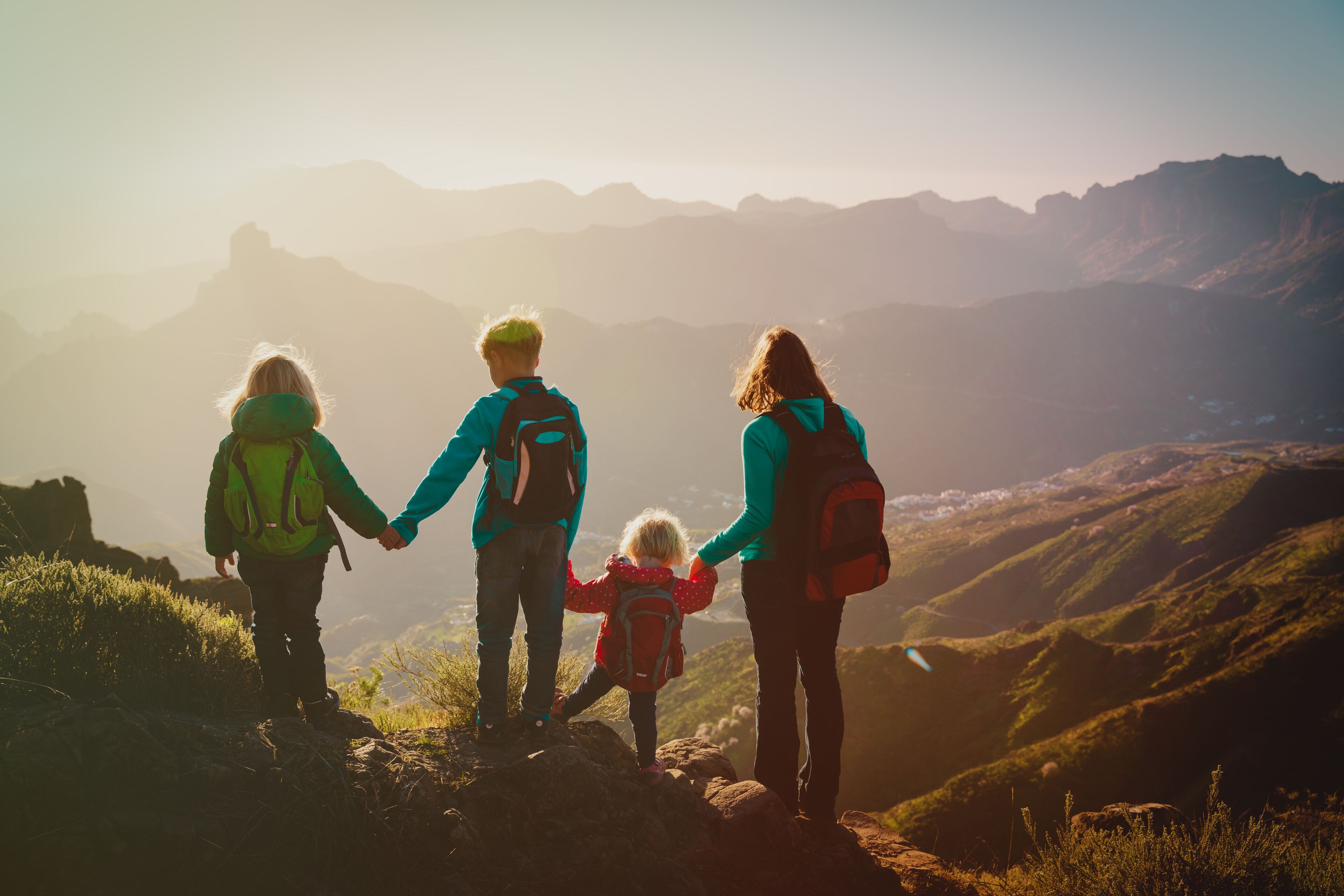 A family of four on a mountain ridge with a clear view of distant mountains.