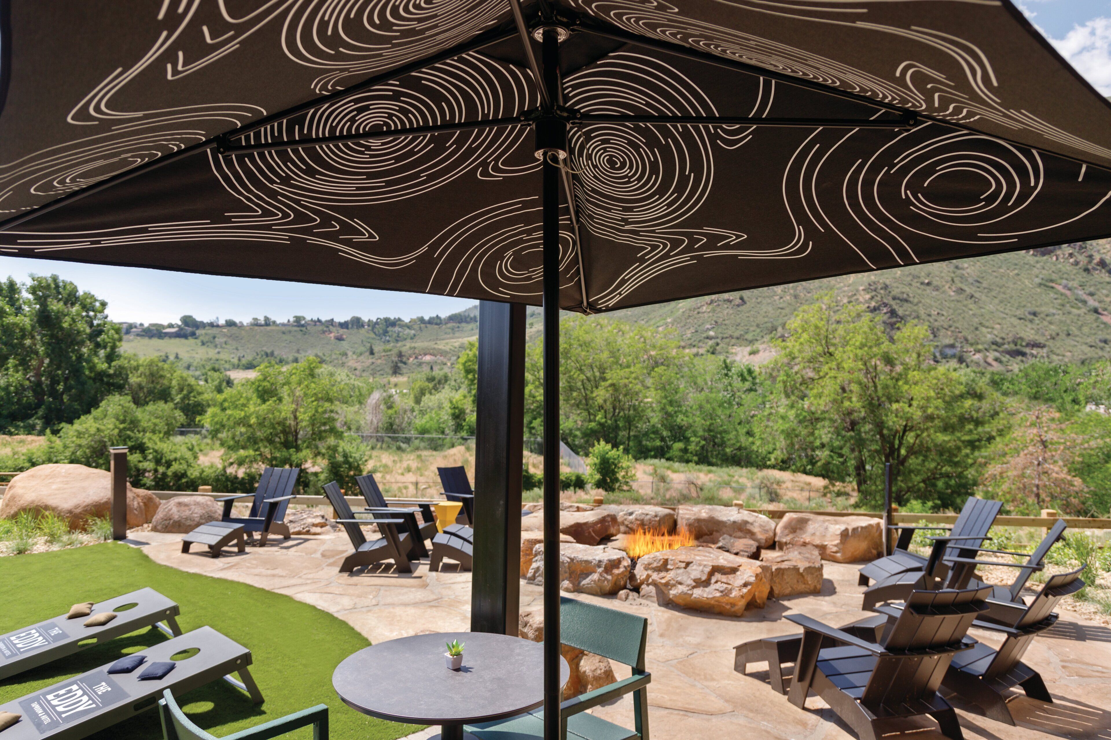 Un patio exterior con sillones de descanso, una mesa y un paraguas decorativo.