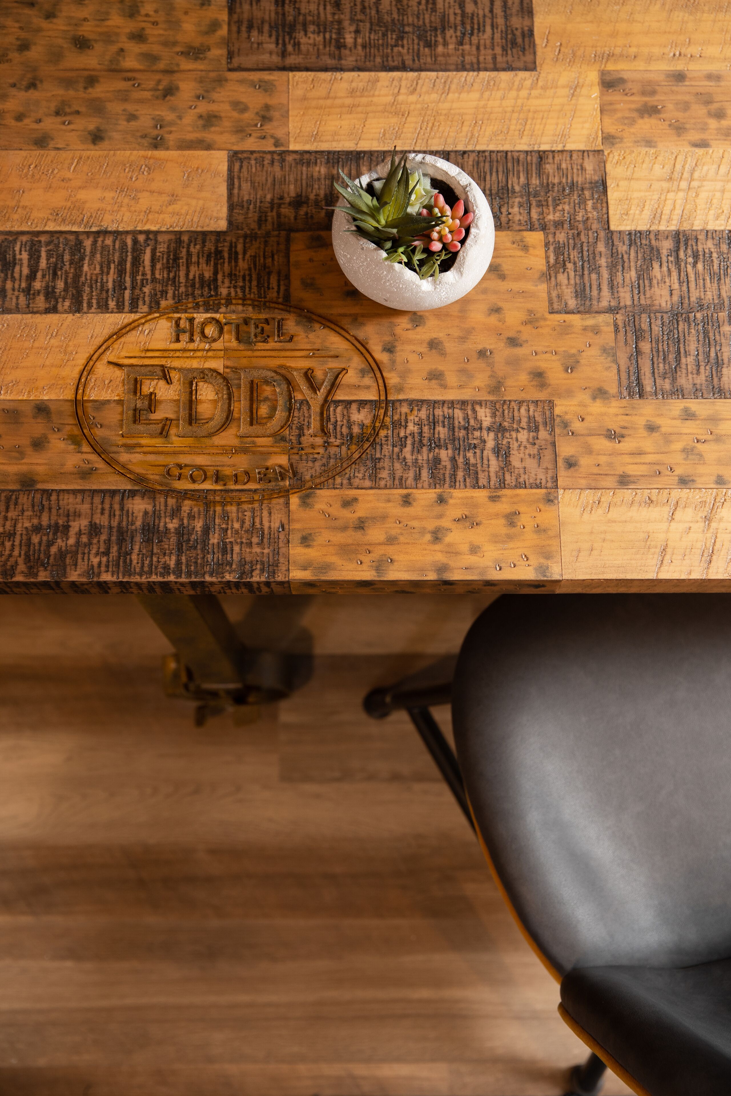 A wooden table with a plaque reading "HOTEL EDDY GOLDEN" and a small potted plant on it.