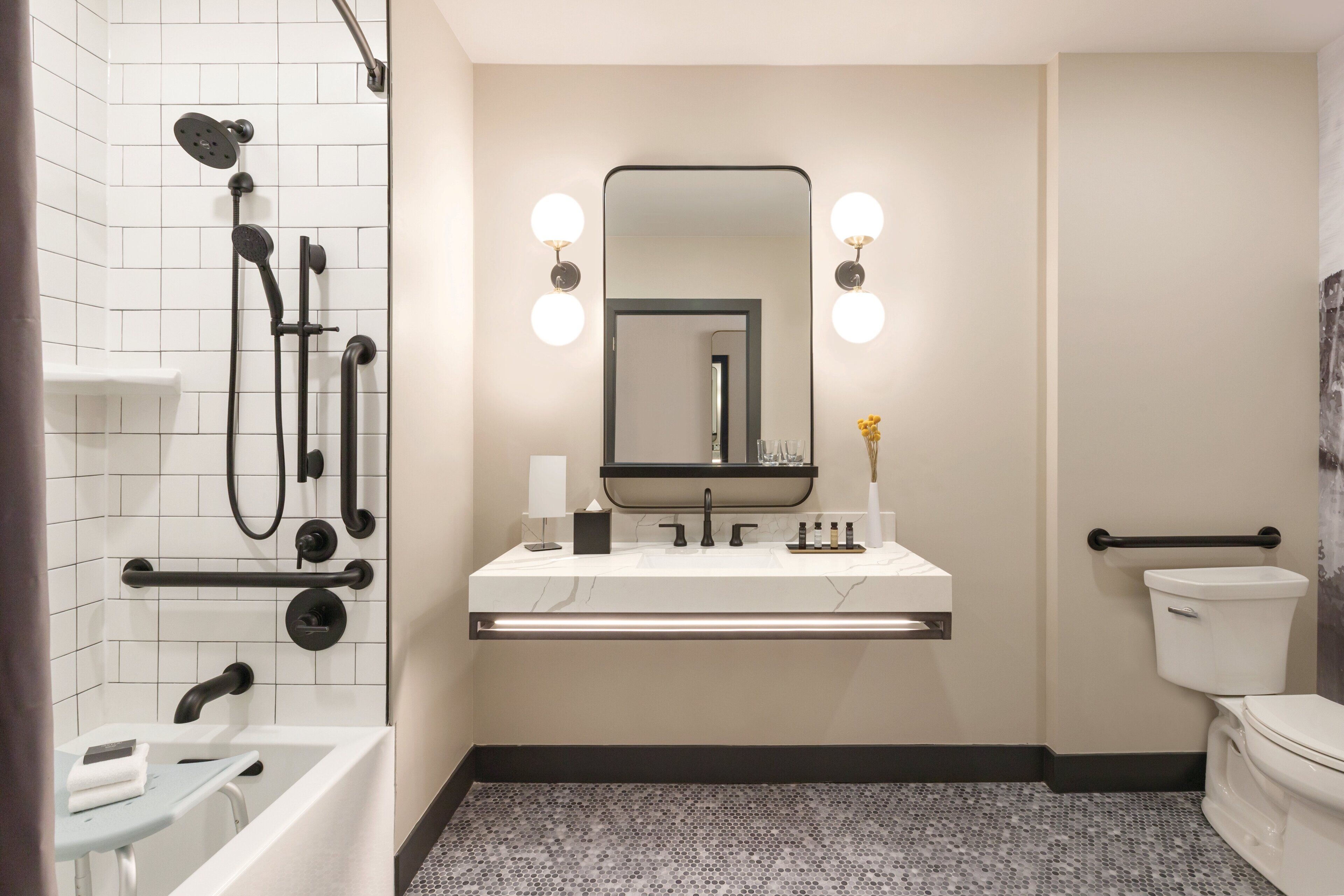 Un baño moderno con un lavamanos blanco, grifería negra, un espejo grande con luces y un inodoro.