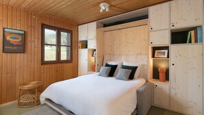 Ein Zimmer mit Holzwänden, einem Bett, eingebauten Stauraum und einem gerahmten Bild an der Wand.