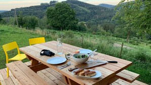 Ein Holztisch draußen mit Blick auf eine bewaldete Hügelkette im Hintergrund.