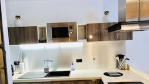 Una cocina moderna con microondas integrado, un lavamanos con grifo y una estufa.