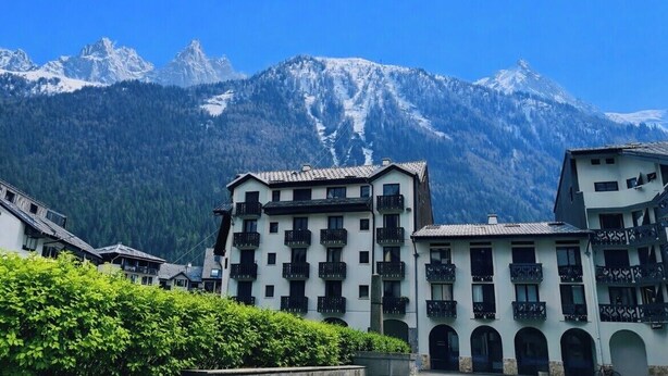 Un edificio con varios balcones, con montañas al fondo y un cielo despejado.