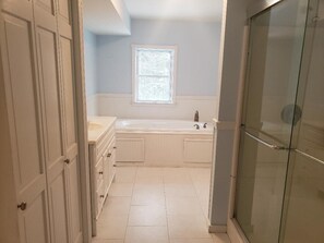 Bagno con vasca, finestra e box doccia in vetro.