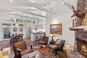 A spacious living area with a fireplace, leather chairs, a dining table, and a kitchen in the background. - Carmel's Wy Knot: Beautiful remodel in Carmel-by-the-Sea! (Carmel)