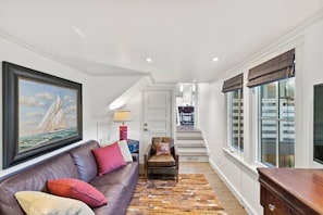 A hallway with a brown leather sofa, a patterned rug, a framed painting, and a staircase leading to another room. - Carmel's Wy Knot: Beautiful remodel in Carmel-by-the-Sea! (Carmel)