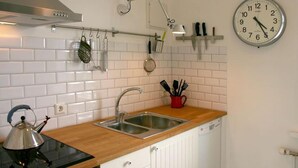 Une cuisine équipée d’un évier, d’une bouilloire et d’ustensiles de cuisine posés sur le plan de travail.