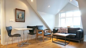 Un espacio habitable moderno estilo loft, con una mesa de comedor, dos sillas, un sofá y una mesa baja.