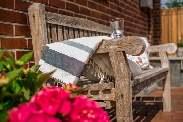 A wooden bench with a striped cushion and a glass of water.