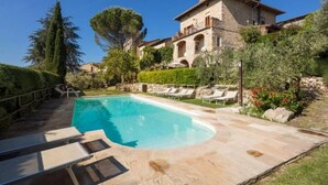 A pool area with lounge chairs and a stone building with arches. - Giovanna apartment on two levels overlooking the swimming pool (Castel San Gimignano)