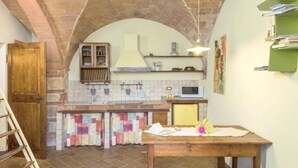A kitchen with a brick arch, a wooden table, and a microwave. - Giovanna apartment on two levels overlooking the swimming pool (Castel San Gimignano)