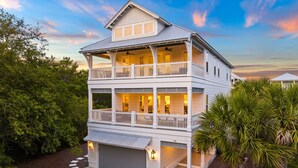 Une maison à deux étages avec un balcon à l’étage supérieur, un garage et un jardin bien entretenu.