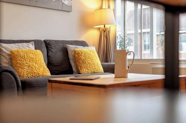 A modern living room with a sofa, yellow cushions, a lamp, and a coffee table.