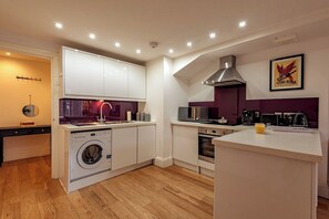 A modern kitchen with a built-in washing machine, a microwave, and a coffee maker.