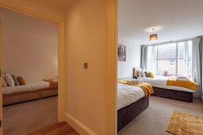 A hotel room with two beds, a large window, and a view of the outside.