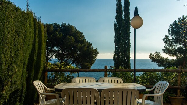 Une terrasse extérieure avec une table ronde et quatre chaises, donnant sur une étendue d’eau.