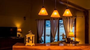 A cozy room with a wooden ceiling, a television on a stand, and a window with curtains. - Cozy Cabin, Mountain View, AC, Porch, Fireplace, Wildlife, 4 mi to town. (Bozeman)