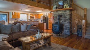 A spacious living area with a high ceiling, wooden staircase, and a stone fireplace. - Cozy Cabin, Mountain View, AC, Porch, Fireplace, Wildlife, 4 mi to town. (Bozeman)