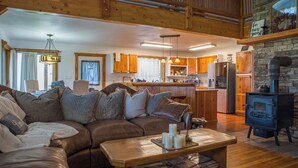 A cozy living room with a brown leather sofa, wooden coffee table, and a fireplace. - Cozy Cabin, Mountain View, AC, Porch, Fireplace, Wildlife, 4 mi to town. (Bozeman)