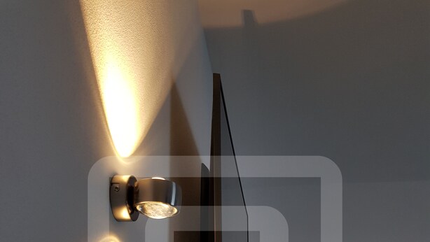 Een modern wandlamp die een warme gloed op de muur werpt.