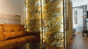 A modern living room with a brown leather sofa, a round black coffee table, and a textured wall with a marble-like pattern. - Cosmopolitan Boutique Rambla (Barcelona)