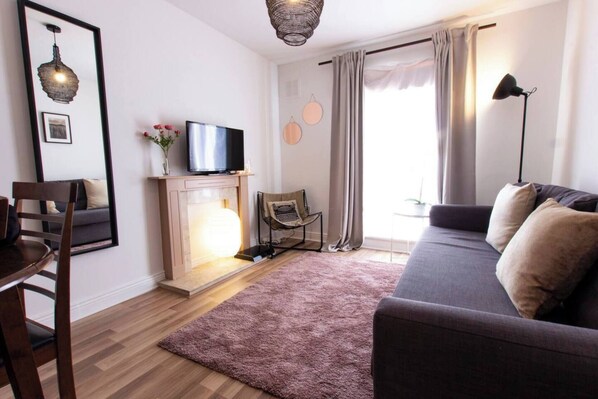 A living room with a sofa, a television, a fireplace, and a chair.