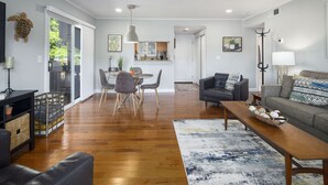 A spacious living room with a grey sofa, a coffee table, and a dining area with a table and chairs.